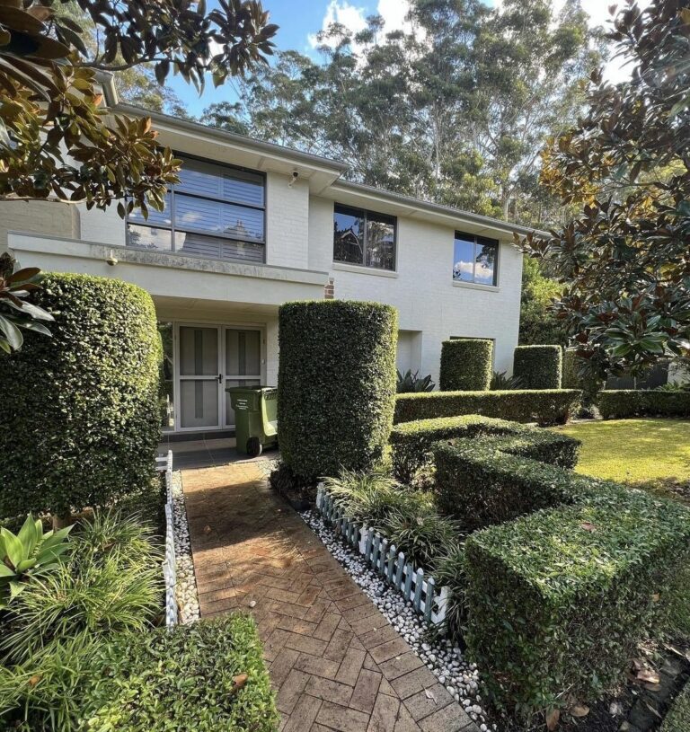 Sculpted topiary hedges across the front of a two storey Sydney home.