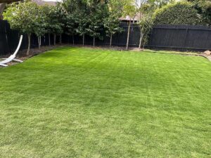 Wide freshly mown lawn enclosed by a dark boundary fence.